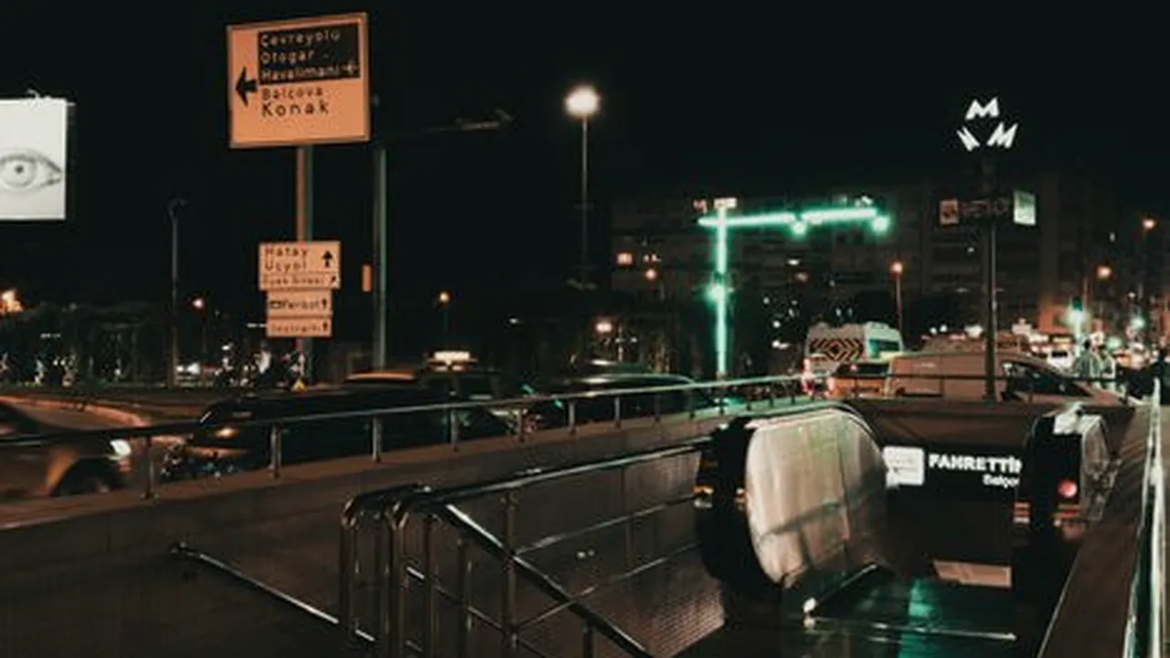 rua movimentada à noite com placas de sinalização apontando para direções diferentes, luzes de trânsito e prédios ao fundo