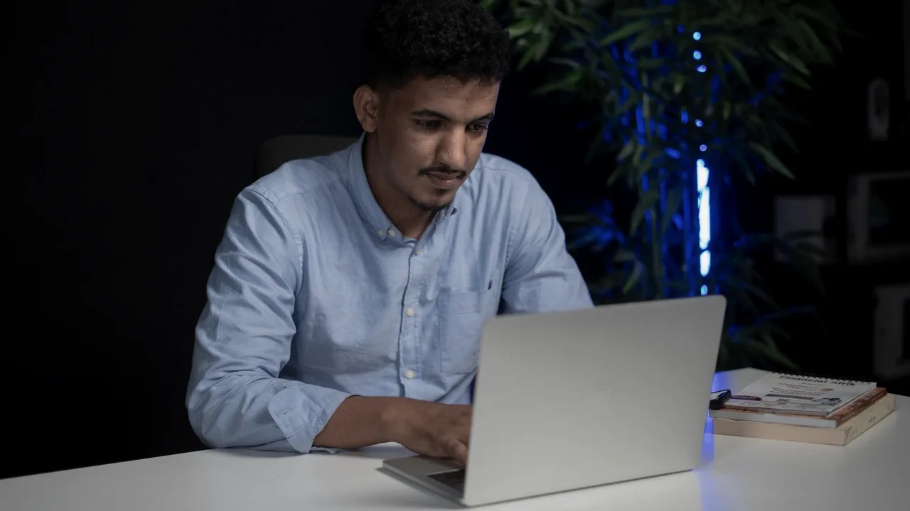 pessoa concentrada trabalhando em notebook num escritório escuro à noite
