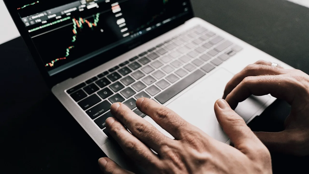 Mãos sobre um notebook conferindo um gráfico na tela