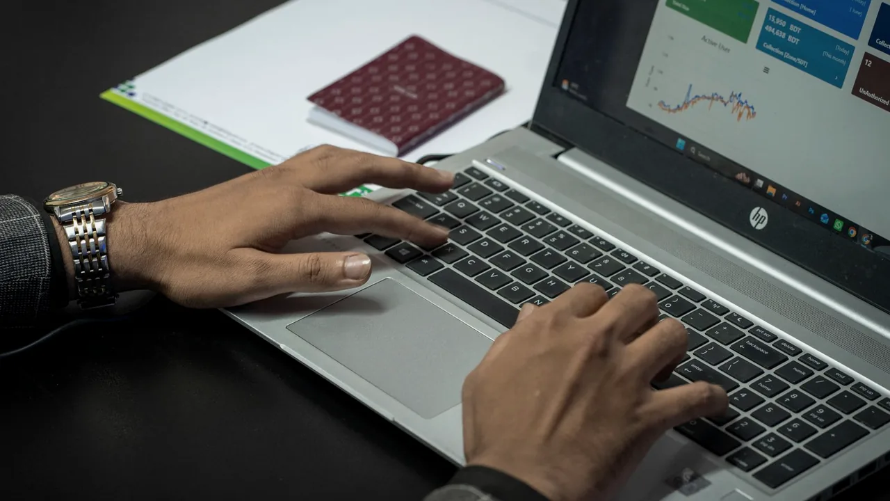 Mãos digitando em um notebook com um painel de métricas na tela