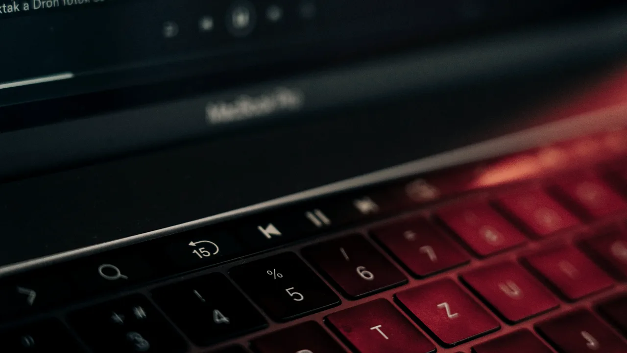 Close-up de teclado de notebook iluminado por luz vermelha, em ambiente escuro